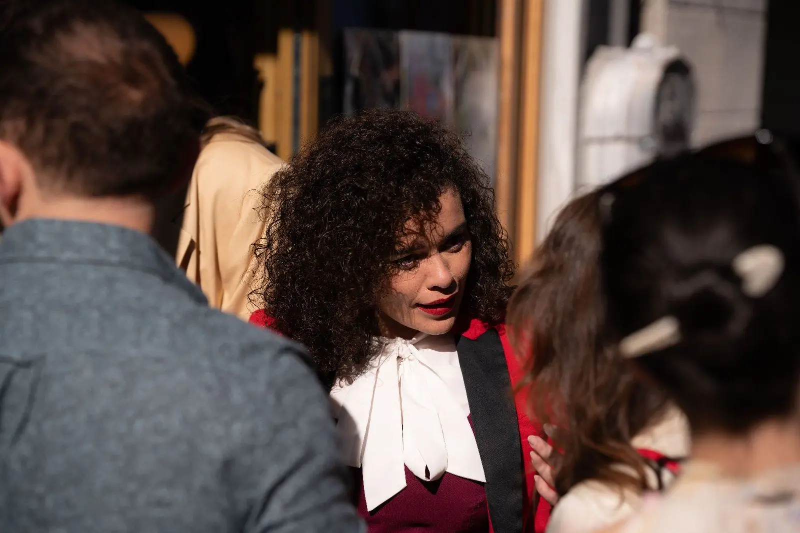 A guest with curly hair and a white bow collar talks with friends in the crowd.